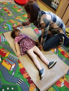 Nauczycielka obrysowuje kontur dziecka2