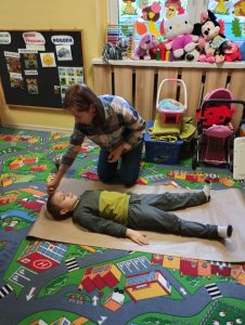 Nauczycielka obrysowuje kontur dziecka