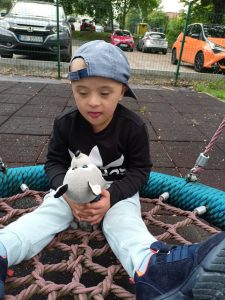 Chłopczyk bawi się na huśtawce swoim misiem