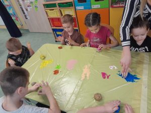 Dzieci malują kamyczki przy pomocy paluszków