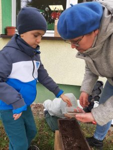 Chłopiec sadzi nasionka z pomocą wychowawczyni