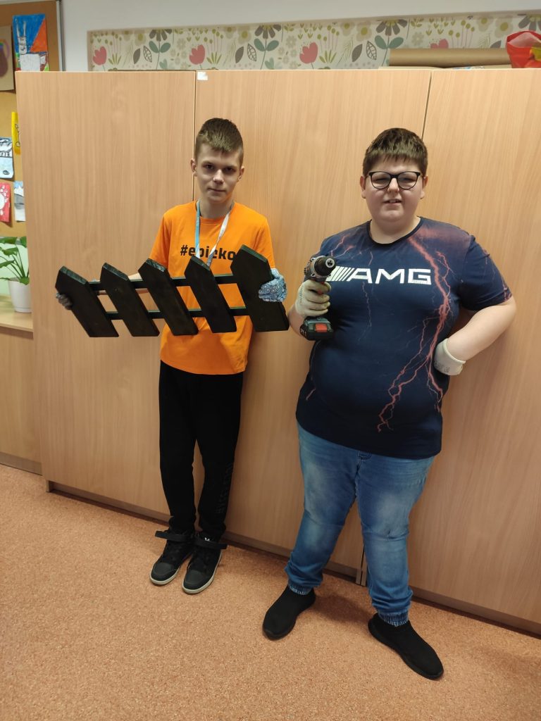 uczniowie skręcają drewniane elementy na dekorację do szkolnego ogrodu