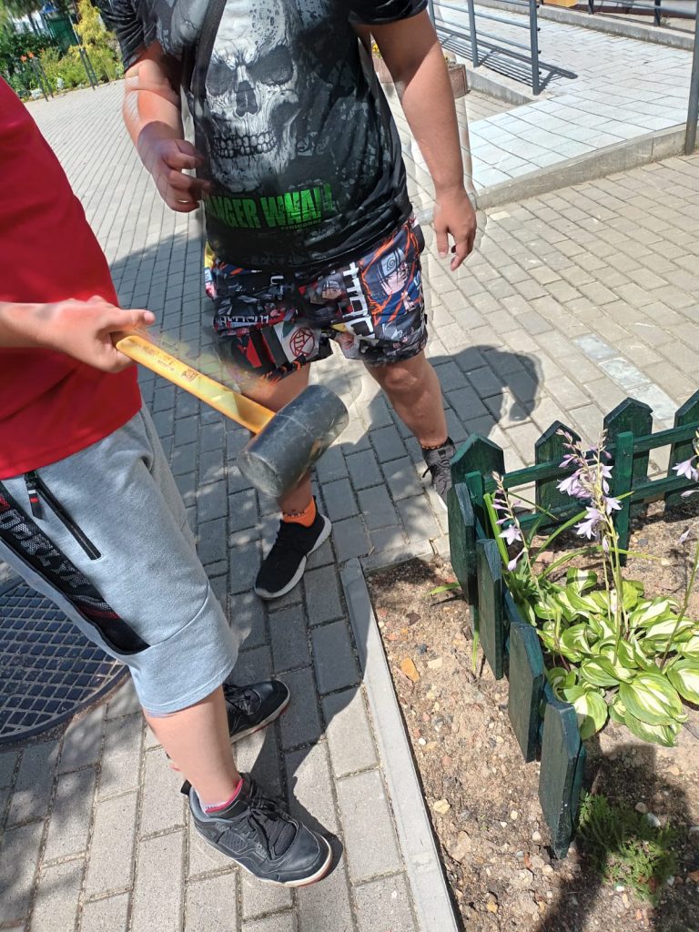 uczniowie instalują własnoręcznie wykonany płotek ogrodowy